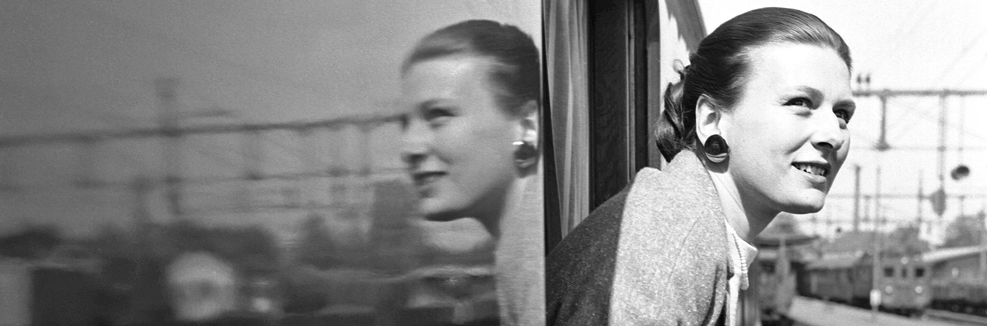 Kvinna på tåg ser ut genom fönster. Foto Seved Walther/Järnvägsmuseet.